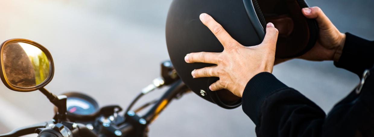DirectAsia Insurance_A person sitting on a motorcycle, holding the motorcycle helmet