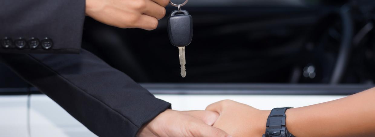 DirectAsia Insurance_car salesman handing over the key for a new car to a young businessman in front of the white car